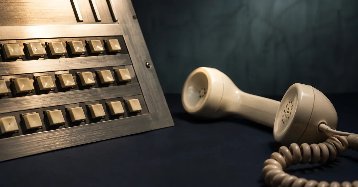 A telephone switchboard with square buttons beside a cream handset
